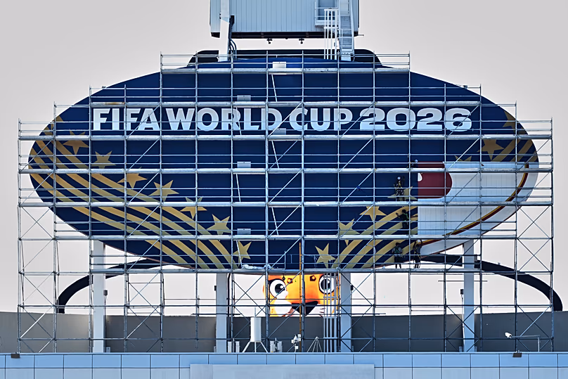 Des travailleurs couvrent une pancarte des Chiefs de Kansas City pour la Coupe du Monde de la FIFA 2026 alors que les travaux se poursuivent pour transformer le stade Arrowhead en stade de Kansas City, le 8 juin 2026.