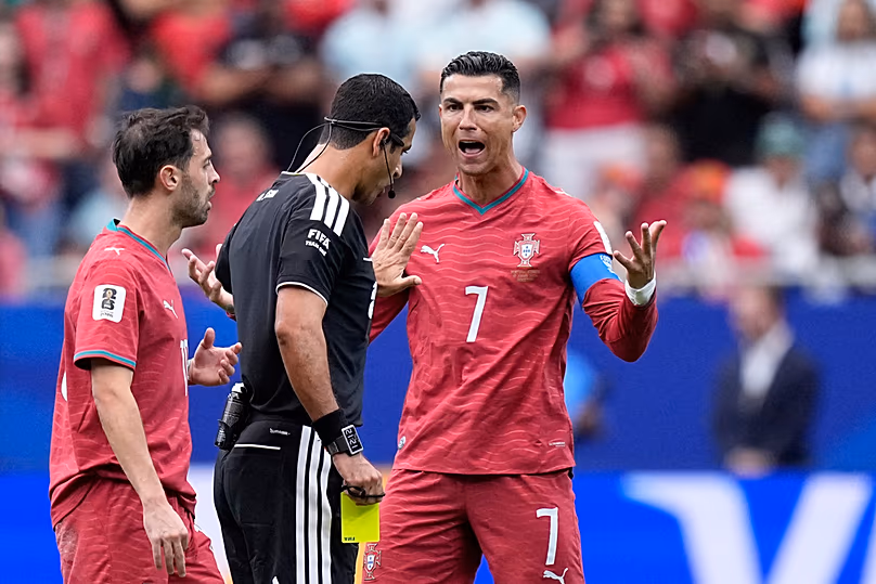 Le Portugais Cristiano Ronaldo se dispute avec l'arbitre Abdulrahman Al-Jassim, du Qatar, après avoir montré un carton jaune à Bernardo Silva, lors du match de football du Groupe K contre la RD Congo