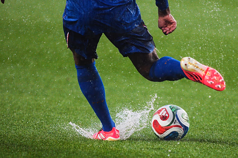 Le Français Jules Koundé donne un coup de pied au ballon alors que de l'eau éclabousse sur le terrain à la suite d'un retard météorologique lors du match du Groupe I de la Coupe du monde contre l'Irak, à Philadelphie, le lundi 22 juin 2026.