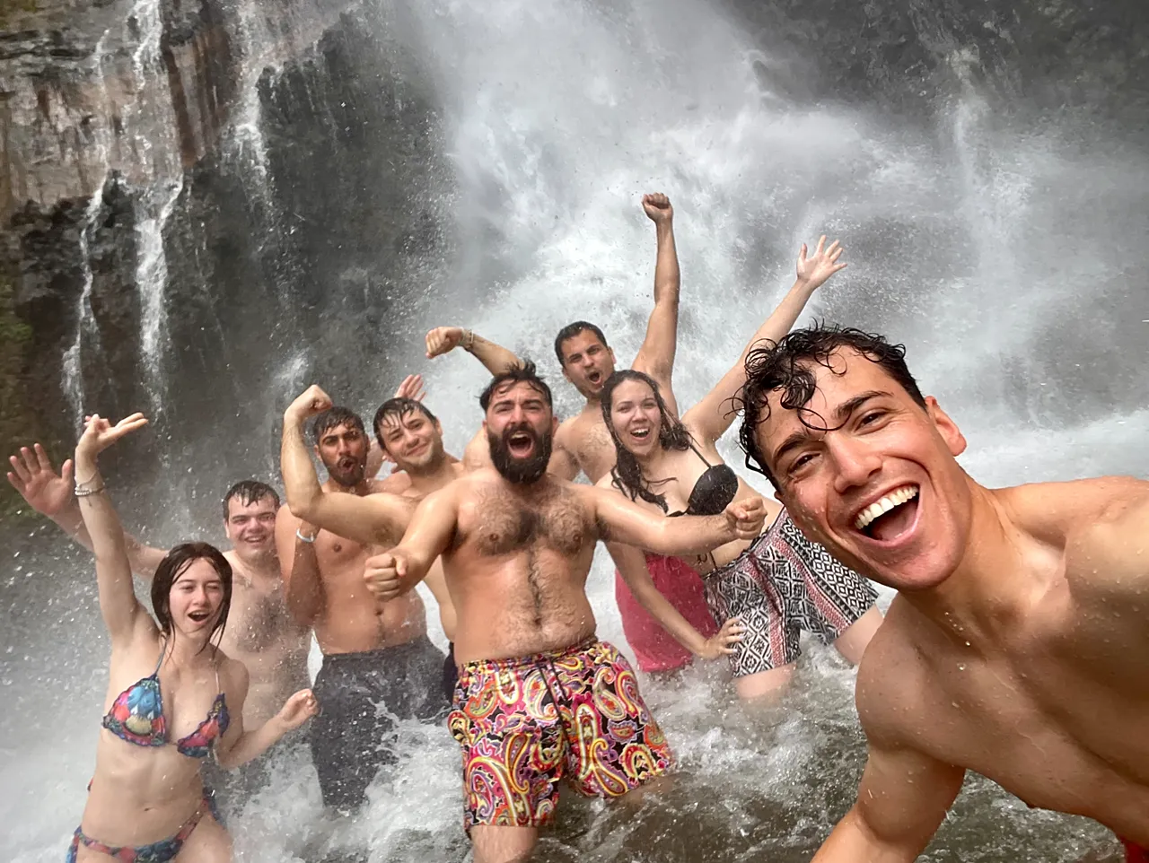 Les voyageurs de WeRoad prennent un selfie de groupe sous une cascade en Indonésie