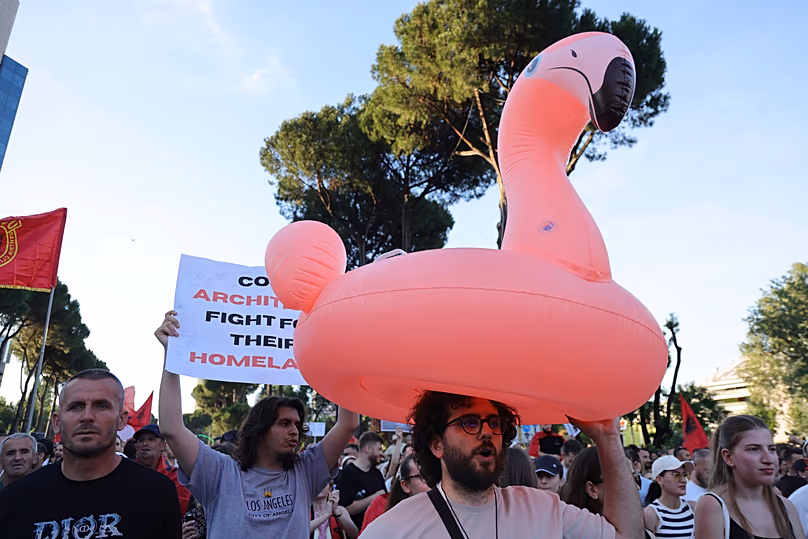 Un manifestant porte un flotteur de flamants roses lors d'un rassemblement à Tirana, le samedi 13 juin 2026.