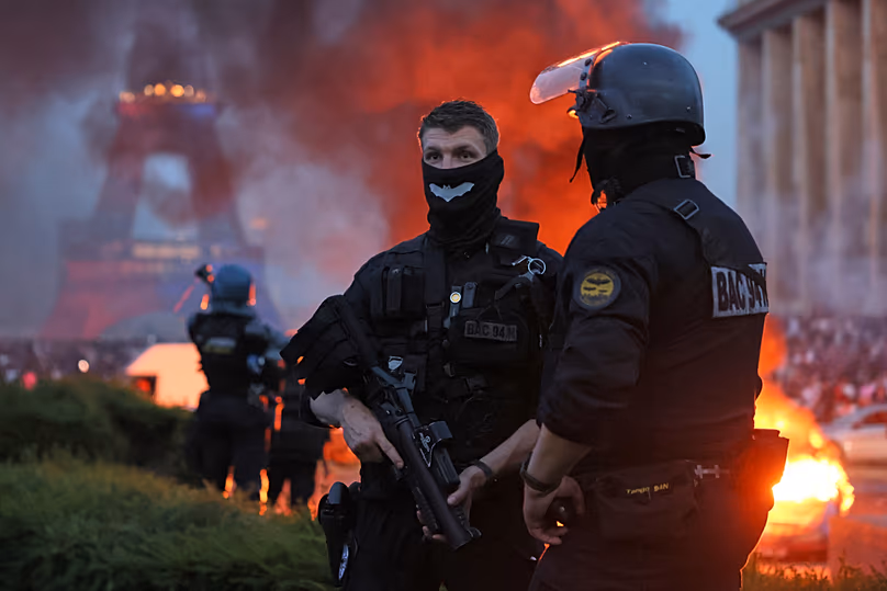 Une voiture brûle et un feu d'artifice explose alors que la police regarde les supporters du PSG célébrer à Paris, le samedi 30 mai 2026, après la finale de la Ligue des Champions entre le PSG et Arsenal.