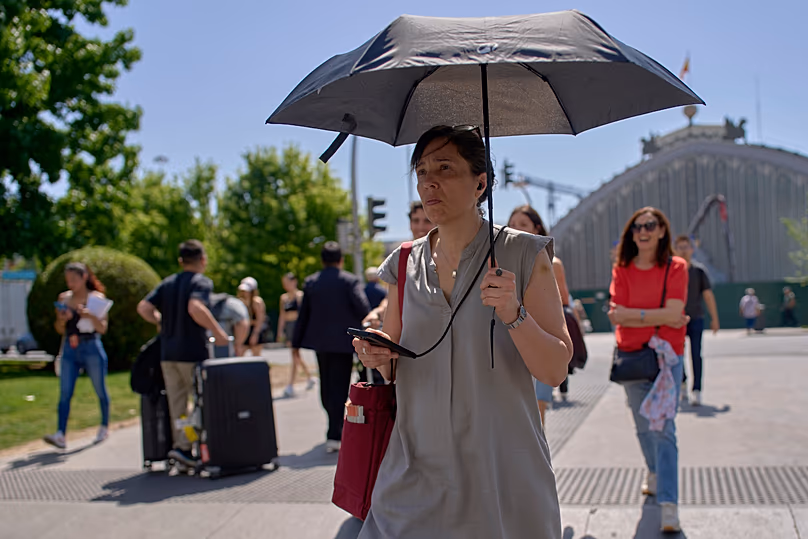 Une femme se protège avec un parapluie lors d’une chaude journée à Madrid, en Espagne, le mercredi 27 mai 2026.