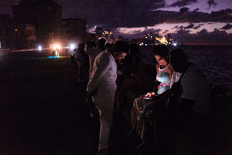 Des gens passent la nuit dans le noir sur le Malecón lors d'une panne d'électricité à La Havane, le 21 mars 2026.