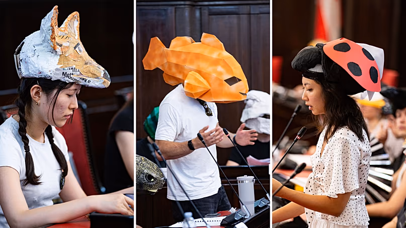 Les gens du Parlement des Espèces Vivantes portent des masques en papier mâché pour représenter des animaux.