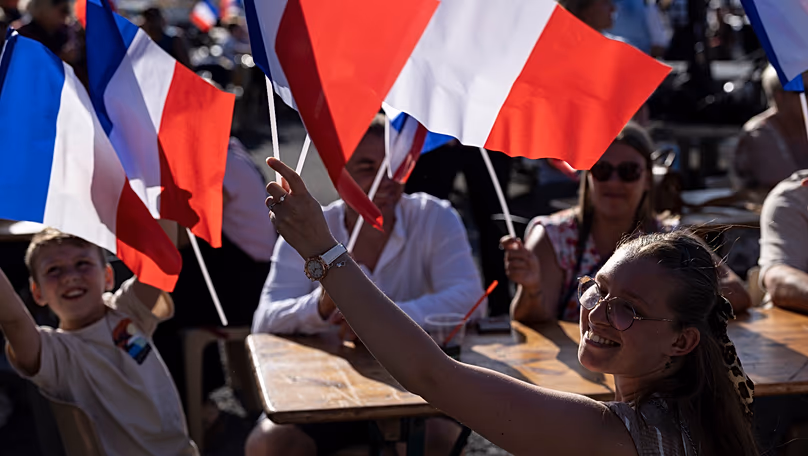 Des gens brandissent des drapeaux français lors d'un rassemblement en présence du président du Rassemblement national d'extrême droite Jordan Bardella et de la leader d'extrême droite Marine Le Pen à Liévin, le 4 juillet 2026.