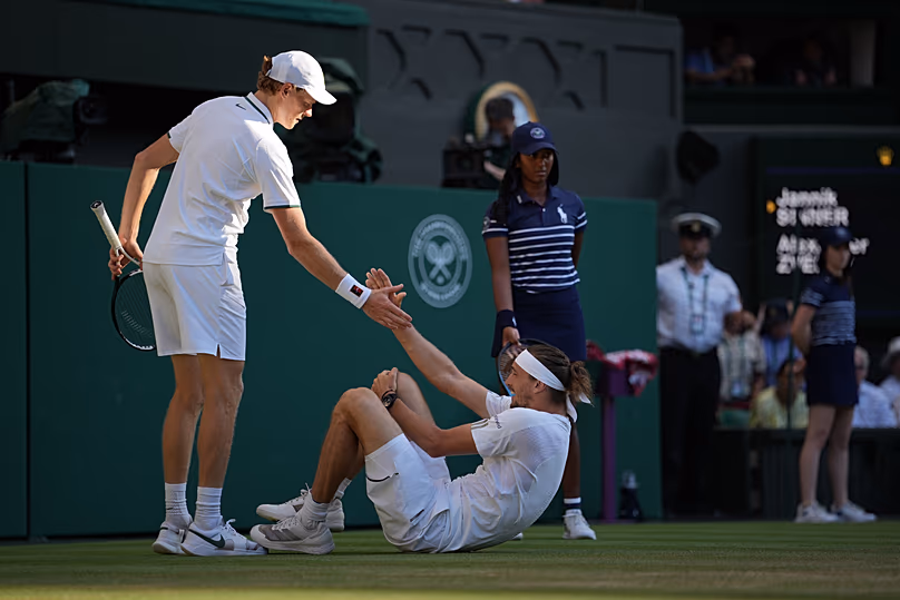 L'Italien Jannik Sinner, à gauche, aide l'Allemand Alexander Zverev qui est tombé lors de la finale du simple messieurs aux championnats de tennis de Wimbledon à Londres, le dimanche 12 juillet 2026.
