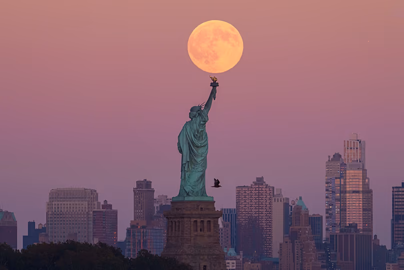 ARCHIVES - La super lune des récoltes se lève derrière la Statue de la Liberté et l'horizon de Brooklyn, le 6 octobre 2025, à Jersey City, New Jersey.