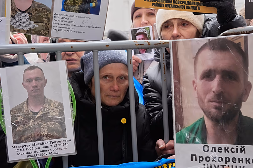 Des gens tiennent des photos de leurs proches alors que des soldats ukrainiens reviennent de captivité lors d'un échange de prisonniers de guerre dans la région de Tchernyhiv, le 11 avril 2026.