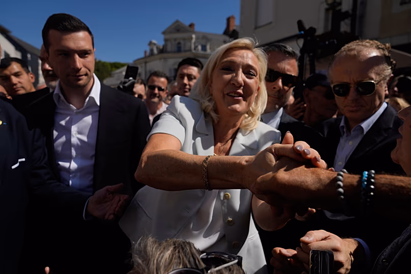 La dirigeante d'extrême droite Marine Le Pen et le président du Rassemblement national d'extrême droite Jordan Bardella arrivent pour visiter un marché à La Flèche, dans l'ouest de la France, le 8 juillet 2026.