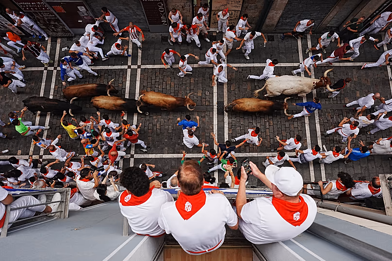 Les fêtards courent aux côtés du taureau de combat de La Palmosilla lors de la sixième course de taureaux de la fête de San Fermín, le 12 juillet 2026.
