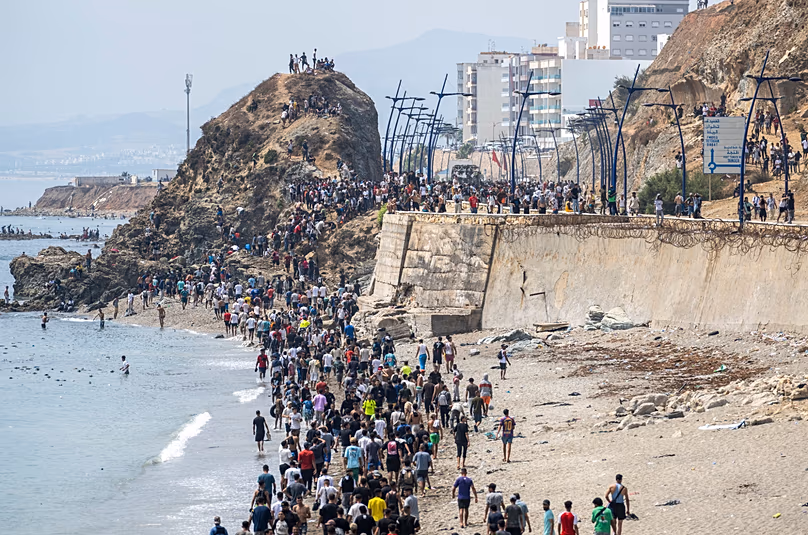 Des gens marchent sur une plage après avoir tenté de passer de la ville de Fnideq, dans le nord du Maroc, à l'enclave espagnole de Ceuta, le vendredi 31 juillet 2026.