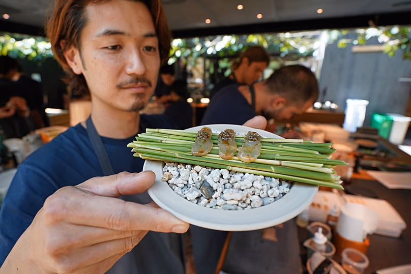 Un chef présente un nouveau plat de poisson dans la cuisine du restaurant gastronomique Noma avant sa nouvelle saison à Copenhague, au Danemark, le mardi 28 juillet 2026. (AP Photo/James Brooks)