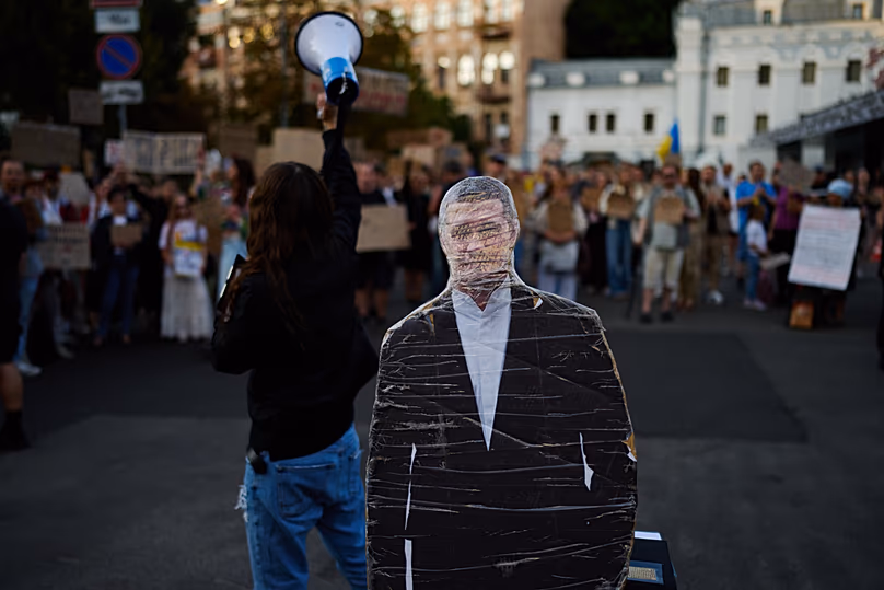 Des gens crient des slogans à côté d'une photo découpée en carton de Mykhailo Fedorov lors d'un rassemblement pour protester contre sa destitution de son poste de ministre ukrainien de la Défense à Kiev, le vendredi 14 août 2026.