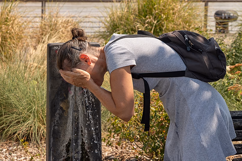 Une femme s'asperge le visage d'eau à une fontaine publique par une chaude journée à Bordeaux, le 13 août 2026.