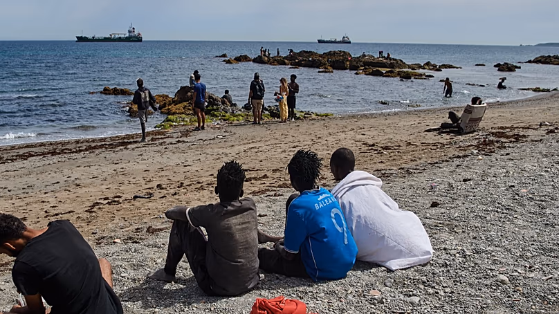 Des migrants arrivés en Espagne depuis le Maroc se rassemblent sur une plage de l'enclave espagnole de Ceuta, le lundi 3 août 2026. (AP Photo/Antonio Sempere)