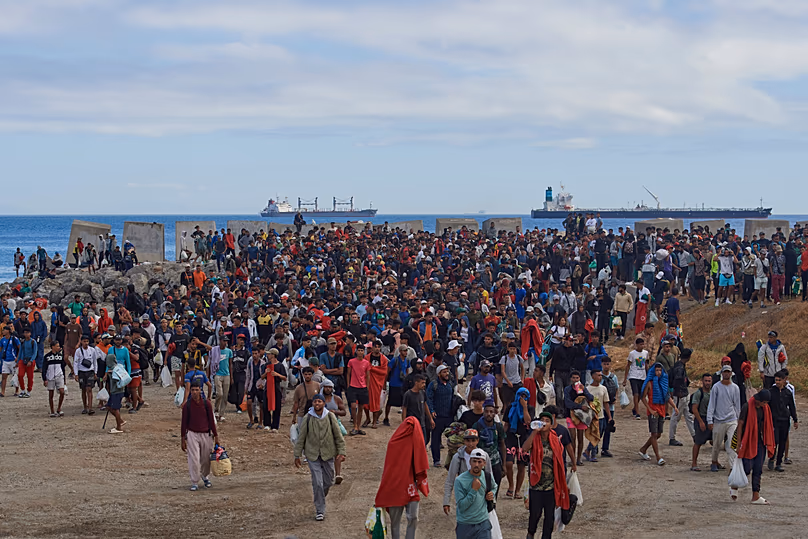 Les migrants qui ont traversé la frontière du Maroc vers l'Espagne sont escortés par la police espagnole vers des abris temporaires après avoir été évacués d'une plage de Ceuta, le 21 août 2026.