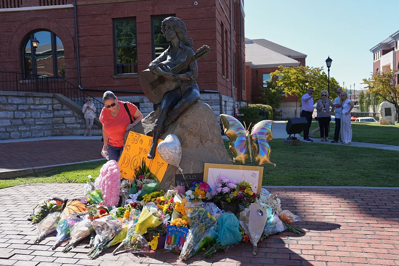 Des gens se rassemblent devant un mémorial de fortune en l'honneur de Dolly Parton devant sa statue à Sevierville, Tennessee, le 25 août 2026.