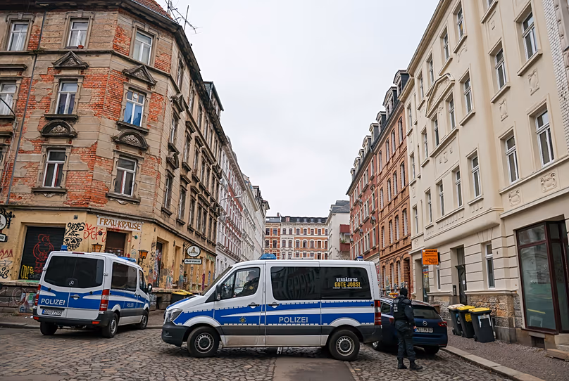 Des véhicules et des agents de police se tiennent debout lors de perquisitions dans le quartier Connewitz de Leipzig, le 26 janvier 2022.