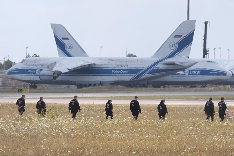 Des policiers traversent un champ sur le terrain de l'aéroport de Leipzig, le 7 août 2026.