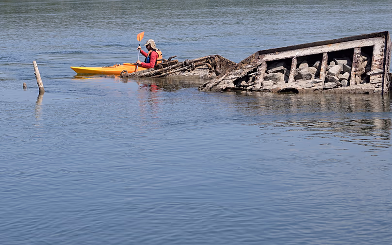 Un canoéiste passe devant l'épave d'un navire de guerre allemand de la Seconde Guerre mondiale sur le Danube près de Prahovo en Serbie, le 29 août 2022