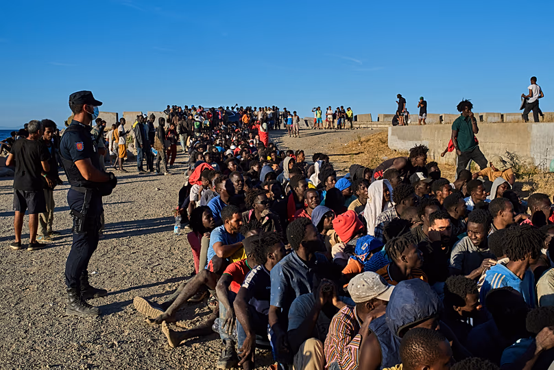 Des migrants arrivés du Maroc vers l'Espagne font la queue pour une distribution de nourriture sur une plage de l'enclave espagnole de Ceuta, le 3 août 2026.