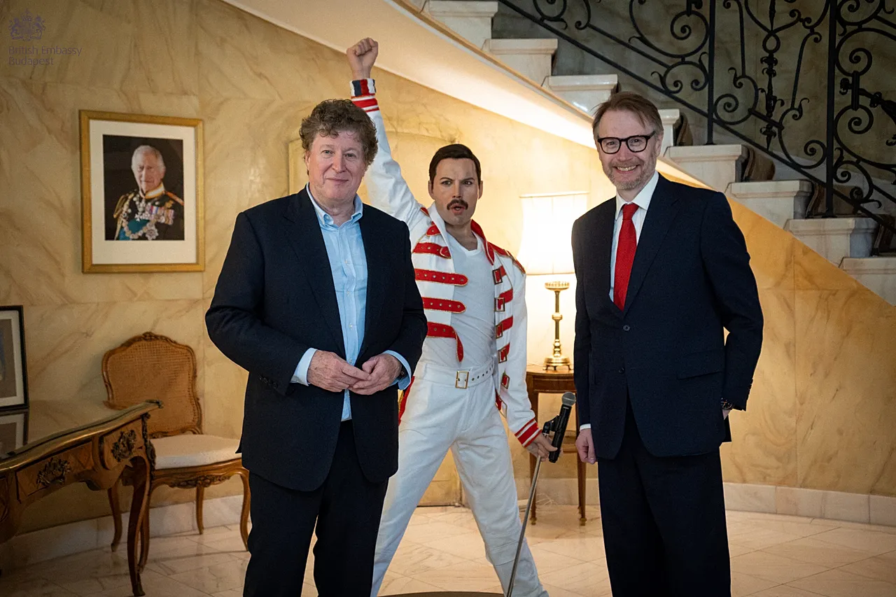 The British ambassador in Budapest Justin McKenzie Smith (r) and Denis O'Regan (l) standing beside Freddie Mercury's wax figure in the foyer of the residence