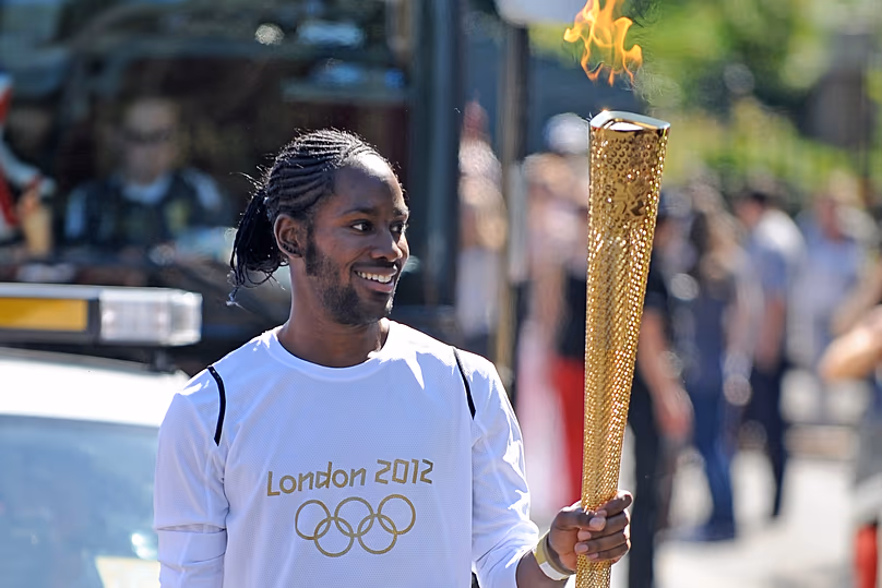 Jason Arday carries the Olympic Flame on the Torch Relay leg between Sutton and Merton, in London - 23 July 2012