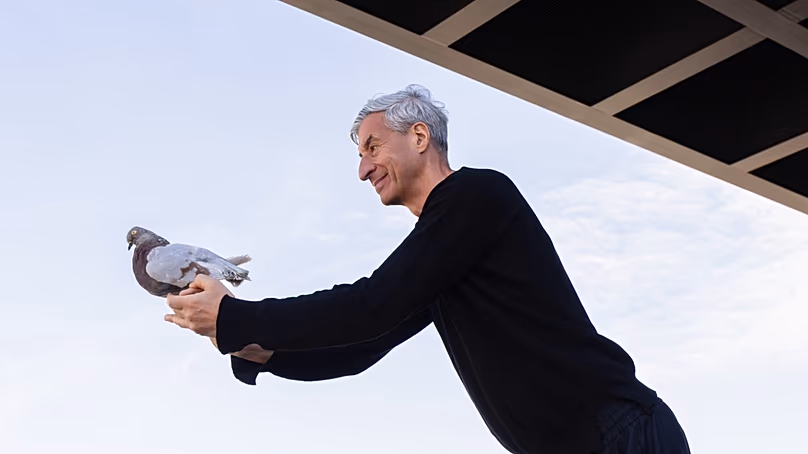 Maurizio Cattelan tient un pigeon taxidermié lors de l'ouverture de son exposition nocturne à la Neue Nationalgalerie de Berlin.