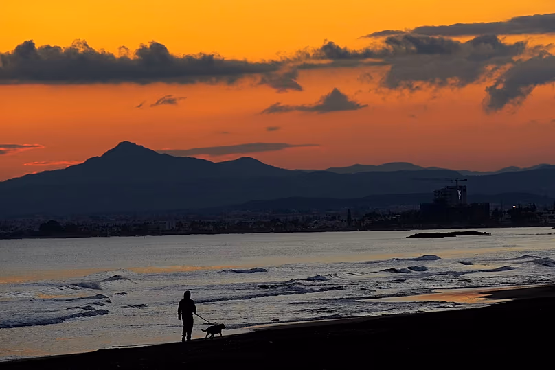 DOSSIER : Un homme marche avec son chien sur la plage au coucher du soleil à Dhekelia près de Larnaca à Chypre, le 31 décembre 2024.