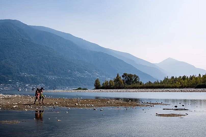 Des gens marchent le long d'un banc de sable formé par les faibles niveaux d'eau dans le delta de la rivière Maggia, à l'endroit où elle rencontre le lac Majeur, à Locarno, le 13 août 2026.