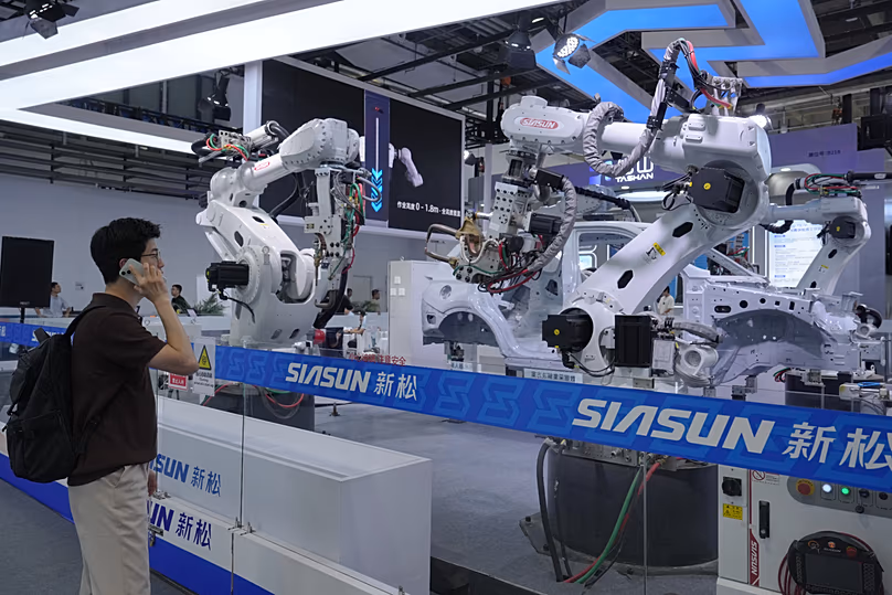DÉPOSER. Un visiteur regarde des bras robotiques pour la production industrielle lors de la Conférence mondiale sur les robots à Pékin, le 19 août 2026.