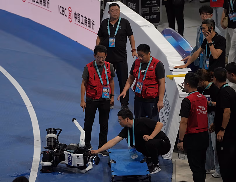 DÉPOSER. Un technicien vérifie un robot après une chute à la fin de la course de 1 500 mètres lors des Jeux mondiaux du robot humanoïde à Pékin, en Chine, le 23 août 2026.