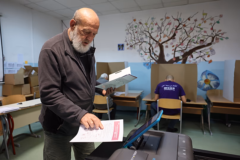 Un homme place son bulletin de vote dans une urne électronique lors des élections générales à Sarajevo, en Bosnie, le dimanche 4 octobre 2026.
