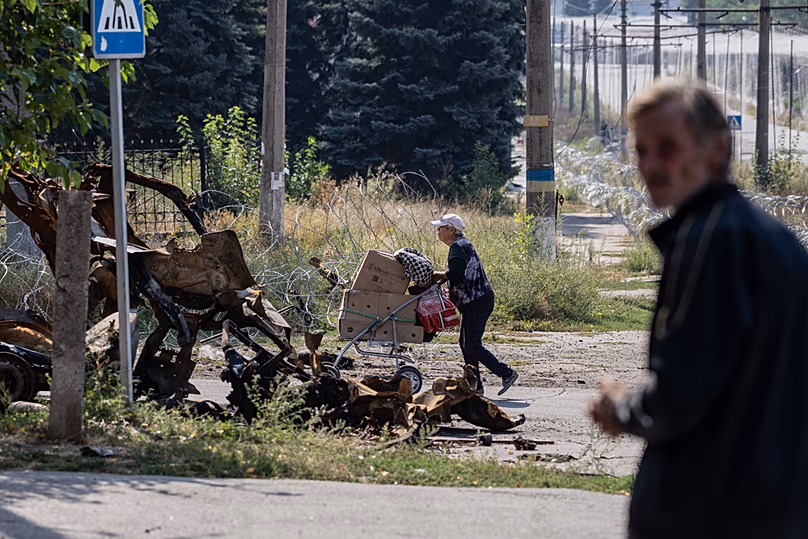 Une habitante locale pousse ses affaires dans une charrette dans les rues de Druzhkivka, dans la région ukrainienne de Donetsk, le 12 septembre 2026.
