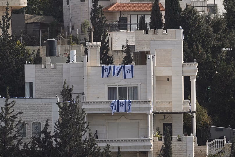 Des drapeaux israéliens sont accrochés à une maison appartenant à des résidents palestiniens lors d'une opération de l'armée israélienne à Hébron, en Cisjordanie occupée, le samedi 24 octobre 2026.
